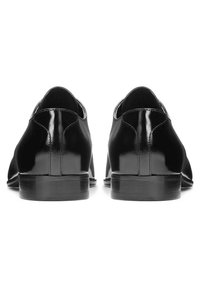 Chaussures en cuir noir avec une finition brillante, dotées d'une silhouette élégante, d'un talon bas et de coutures minimales à l'arrière pour un look raffiné.