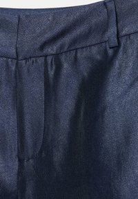 Marinblå byxor med mjuk textur, platt midjeband och diskret glans, med en synlig sidoficka.