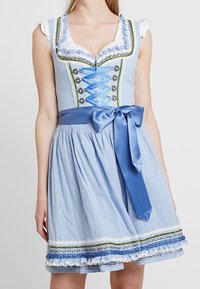 Robe dirndl bleu clair avec un corsage ajusté orné de dentelle, une ceinture en satin bleu et une jupe évasée avec des finitions décoratives.