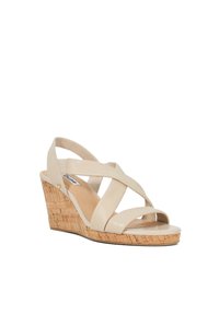 Beige wedge sandaal met gekruiste leren banden, kurktextuur hak, soepele teenband en subtiele logo-detail aan de zijkant.