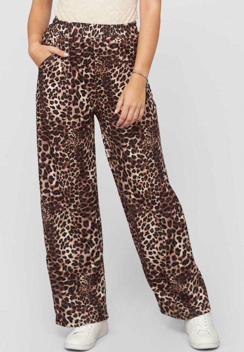 Leopardenprint wijde broek in zachte stof, met een elastische tailleband en zijzakken, gecombineerd met witte sneakers.