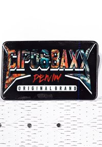 Étiquette de marque en denim rectangulaire noire avec un texte coloré en gras "Eipoobaxx," "Denim" en rouge, et "Original Brand" en blanc sur une surface blanche texturée.