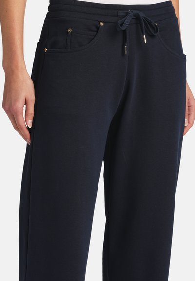 Black drawstring sweatpants with front pockets worn by a person with hands relaxed at sides.