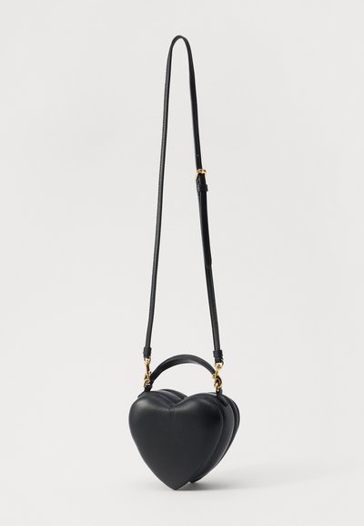 Black heart-shaped handbag made of smooth leather, featuring a detachable strap and gold-tone hardware accents. Compact and structured design.