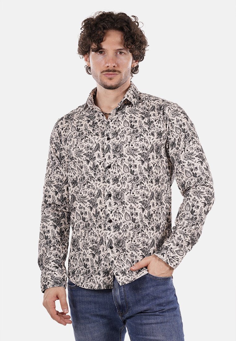 Camicia a maniche lunghe color crema con un intricato motivo floreale nero, colletto e polsini con bottoni. Abbinata a jeans blu.