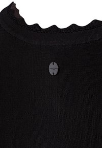Haut tricoté noir texturé avec un col festonné et une petite étiquette ovale noire portant le nom de la marque.