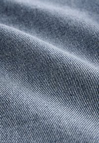 Trapun tkanina svijetloplave boje s finim, paralelnim uzorcima šavova. Tekstura je glatka s blagim sjajem koji reflektira svjetlo.