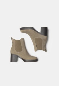 Stivaletti in suede marrone con tacco a blocco, pannelli laterali elasticizzati e linguette per una facile calzata. Accenti testurizzati sui lati.