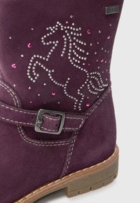 Paarse suede enkellaars met een zilveren en roze rhinestone eenhoornontwerp, een gespaccent en een gestructureerde zool.