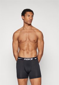 Black Nike boxer shorts with a branded elastic waistband. Smooth, stretchy fabric with a fitted design, extending to the mid-thigh.