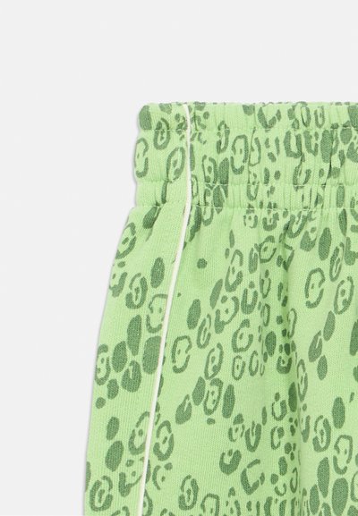 Roheline dressipüksid tekstureeritud kangaga, millel on tume roheline leopardimuster ja elastne vöökoht, millel on valged triibud.