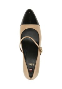 Zapato de tacón alto de cuero beige con punta negra y una delgada correa en el tobillo, presenta un logo dorado en la plantilla y un acabado brillante.