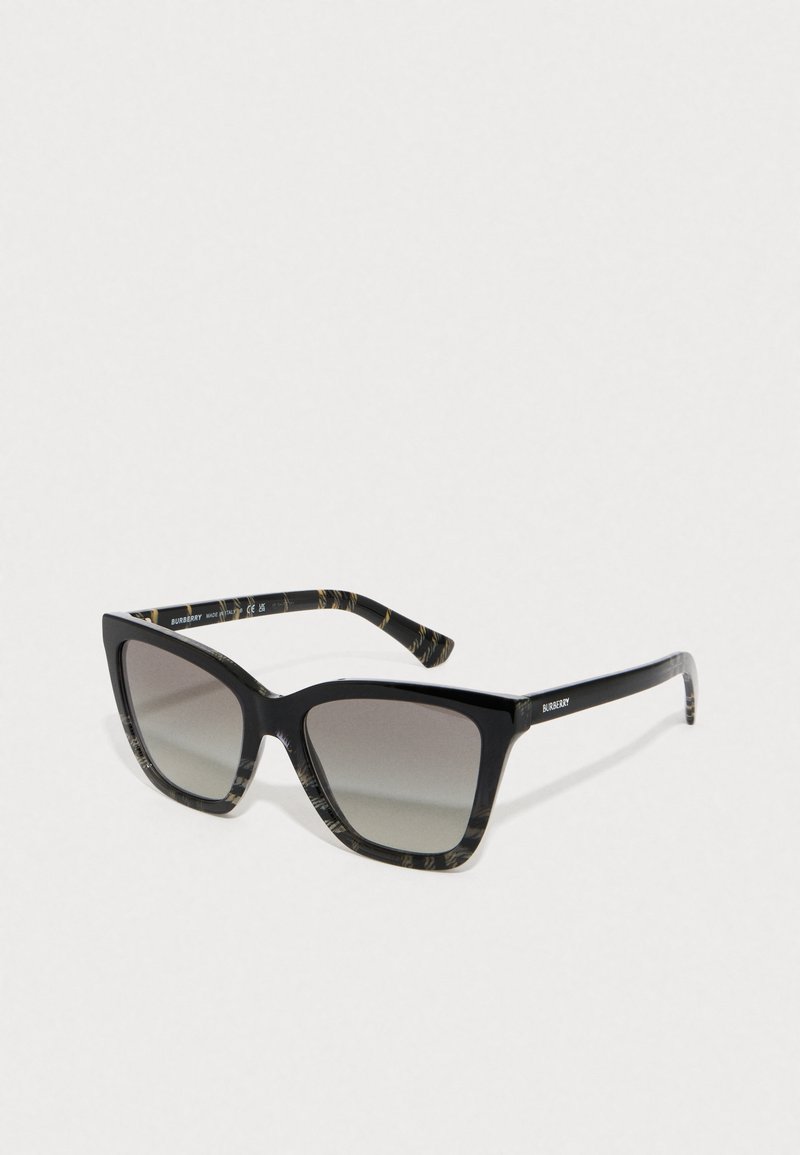 Schwarze Sonnenbrille mit einem breiten, kantigen Rahmen. Graue Verlaufs-Gläser. Die Bügel sind mit einem einzigartigen, gemusterten Design in Schwarz und Beige versehen.