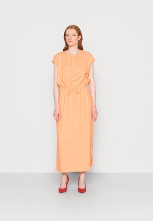 Vestido de linho laranja com mangas curtas e cintura ajustada. Apresenta uma silhueta solta e fendas laterais, combinado com sapatos de salto alto vermelhos.