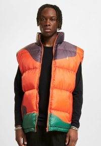 Lysende puffervest med orange, lilla og grønne sektioner, høj krave, lynlås lukning og quiltet tekstur, designet til varme og komfort.