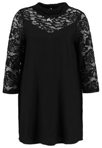 Robe noire longueur genou avec manches longues en dentelle florale et empiècement en dentelle transparente couvrant la poitrine et col montant.