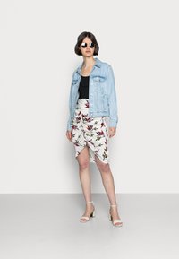 Denim jakk, must tank top, lille lilledetailiga моя на белом, красном и зеленом kolor. Белые блоки-каблуки. Короткие, прямые черные волосы, солнечные очки.