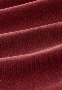 Zachte, gestructureerde stof in een diepe kastanjebruine kleur, met een geribd patroon, overlappende plooien en een glad oppervlak.