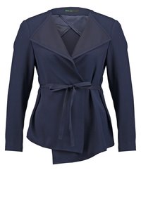 Námornícky modrý blazer s překrytím, zdobený klopovým límcem, dlouhými rukávy a zavazovacím pásem v pase. Hladká textura, strukturovaný tvar.