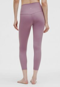 Jasnofioletowe legginsy z wysokim stanem, wykonane z gładkiego materiału, o dopasowanym kroju i długości sięgającej kostek. Brak widocznych logo lub wzorów.