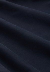 Tkanina w kolorze granatowym o gładkiej teksturze, z subtelnymi falami i równą powierzchnią. Materiał wydaje się lekki i elastyczny.