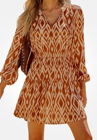 Abito corto arancione e crema con motivo, scollatura a V, maniche lunghe a sbuffo e orlo a balze stratificate. Realizzato in tessuto leggero.
