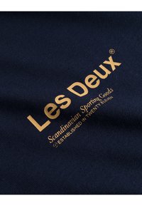 Námornícká látka s vyšívaným zlatým textem "Les Deux" a "Scandinavian Sporting Goods," s uvedeným datem "TWENTY ELEVEN."