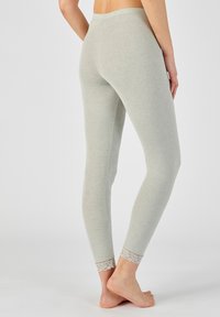 Lichtgrijze leggings met een aansluitend ontwerp, gemaakt van zachte stof, met kantaccenten bij de enkelmanchetten. Soepele textuur, enkellange stijl.