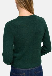 Ciemnozielony sweter o fakturowanym wykończeniu, z okrągłym dekoltem i długimi rękawami. Tył prezentuje czysty, prosty design, podkreślający materiał.