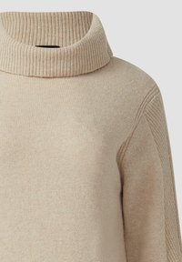Beżowy sweter typu golf z prążkowaną teksturą, z luźnym kołnierzem i lekko zwężającymi się rękawami. Miękka dzianina z detalami na bocznych szwach.