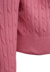 Roze gebreide stof met verticale kabelpatronen en geruite zoom, met gedetailleerde textuur en stiksels van een mouw en lichaam van een trui.