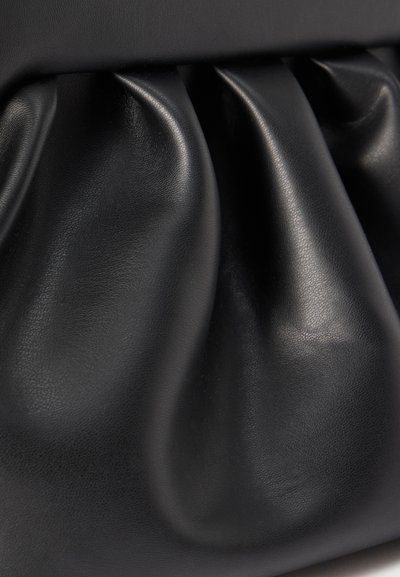 Pehme must nahk, kokku volditud kolme selgelt märgatava kortsuna, mille pind on sile ja veidi läikiv, tõenäoliselt koti või aksessuaari osa.