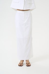 Lang hvit skjørt laget av lettvektstoff, med en tettsittende midjeb�ånd og en rett silhuett. Brukt med minimalistiske brune sandaler.