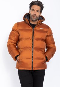Giacca a vento marrone con cappuccio staccabile, chiusura con zip e dettagli neri; presenta un design trapuntato e tasche laterali.