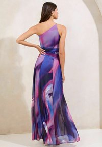 Maxi dress with one shoulder design, featuring flowing fabric in purple and pink hues with abstract patterns. Lightweight and elegant texture.