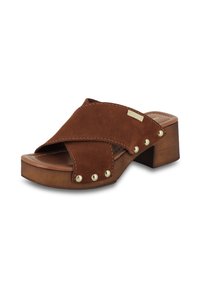 Sandale à glissière en cuir suédé marron avec un design à brides croisées, un talon bloc en bois et des clous dorés sur les côtés. Semelle intérieure en cuir lisse.