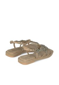 Beige flache Sandalen mit einem verzierten Riemendesign, strukturiertem Material, verstellbarem Knöchelriemen und gepolstertem Fußbett.