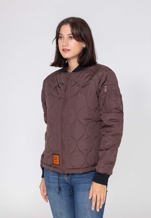 Giacca marrone trapuntata con chiusura a zip, polsini a costine e cordoncino all'orlo. Include un'etichetta arancione e tasche laterali.