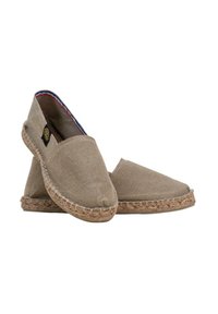 Espadrilles en toile beige avec une semelle en jute naturel, présentant une texture lisse et un design simple. Accents bleus et rouges le long du bord intérieur.