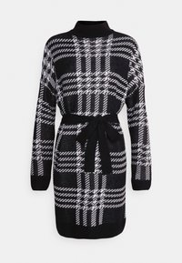 Abito maglione nero e bianco con un motivo a scacchi, maniche lunghe e una cintura legata in vita. Collo alto con polsini a costine.