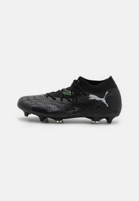 Botas de fútbol negras con parte superior texturizada, cuello de calcetín tejido, acentos verdes y logo plateado. Presenta tacos cónicos para tracción.