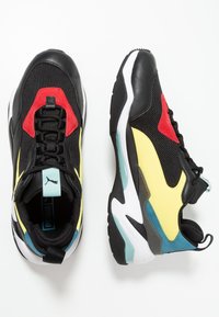 Czarne buty sportowe z siateczką i skórą, z czerwonymi, żółtymi i niebieskimi akcentami, teksturowaną podeszwą i systemem sznurowania.