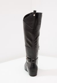 Botte en cuir noir montante avec une fermeture éclair, un bout rond et un accent de boucle en argent au niveau de la cheville. Tige texturée et finition lisse.