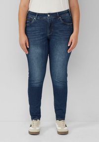 Donkerblauwe denim jeans met een slim fit, voorzien van voorzakken, een knoopsluiting en subtiele vervaging voor textuur. Draag ze met lichte sneakers.