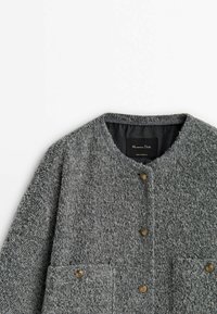 Manteau gris texturé en mélange de laine, avec un col rond, des poches avant et des boutons dorés. Doublure intérieure, design minimal.