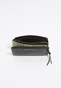 Portefeuille en simili cuir noir et vert avec un motif crocodile texturé, détail de fermeture éclair dorée et plusieurs emplacements pour cartes.