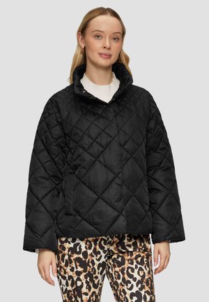 Zwarte, gewatteerde jas met een hoge kraag en een knoopsluiting. Heeft brede mouwen en zijzakken, gecombineerd met een broek met een dierlijk patroon.