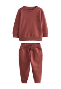 Sweat-shirt couleur rouille et pantalon assorti en tissu doux. Le sweat-shirt présente un col rond, tandis que le pantalon est doté d'une taille élastique et de poignets.