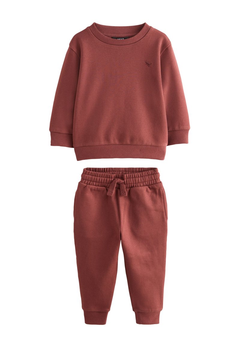 Sweat-shirt couleur rouille et pantalon assorti en tissu doux. Le sweat-shirt présente un col rond, tandis que le pantalon est doté d'une taille élastique et de poignets.