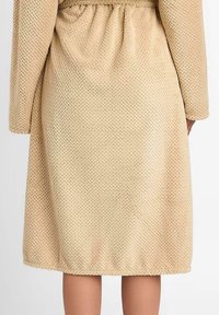 Beżowy, teksturowany szlafrok z elastycznym pasem, długimi rękawami i długością do kolan. Tkanina ma wzór diamentowy na całej powierzchni.